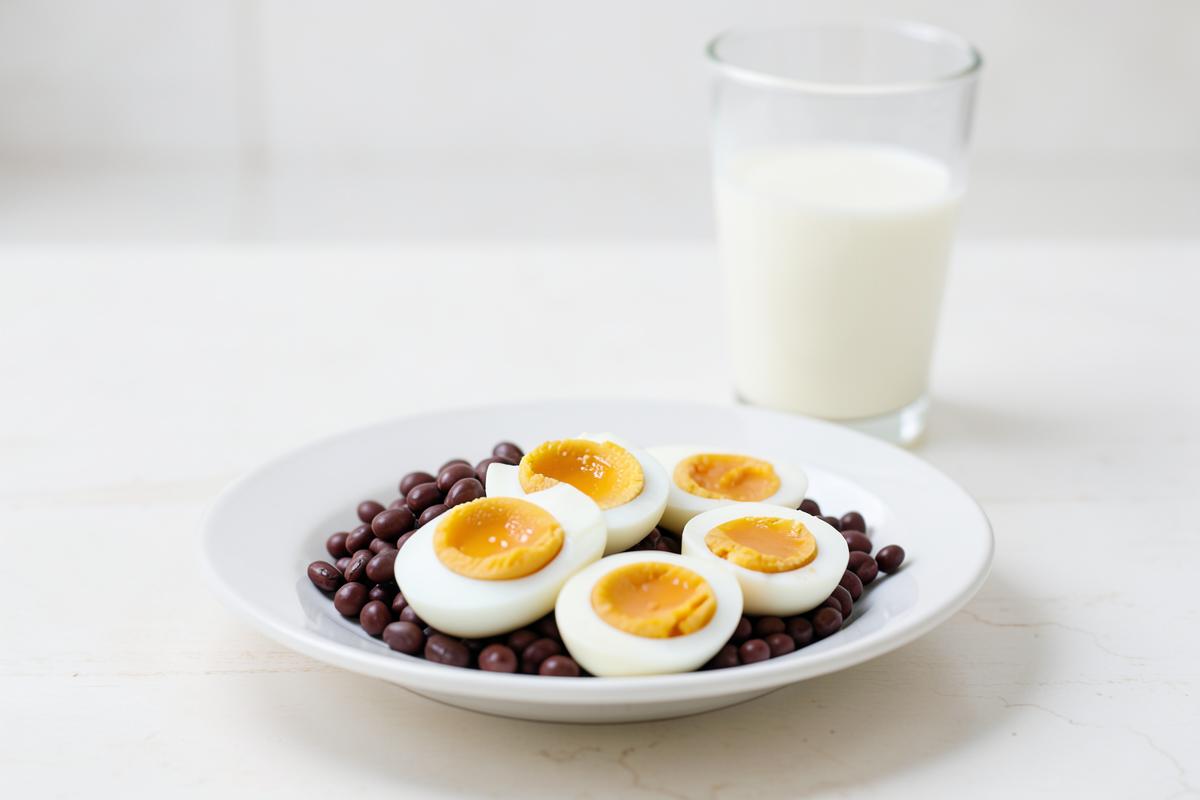Boiled eggs and soy beans on a plate beside a glass of milk