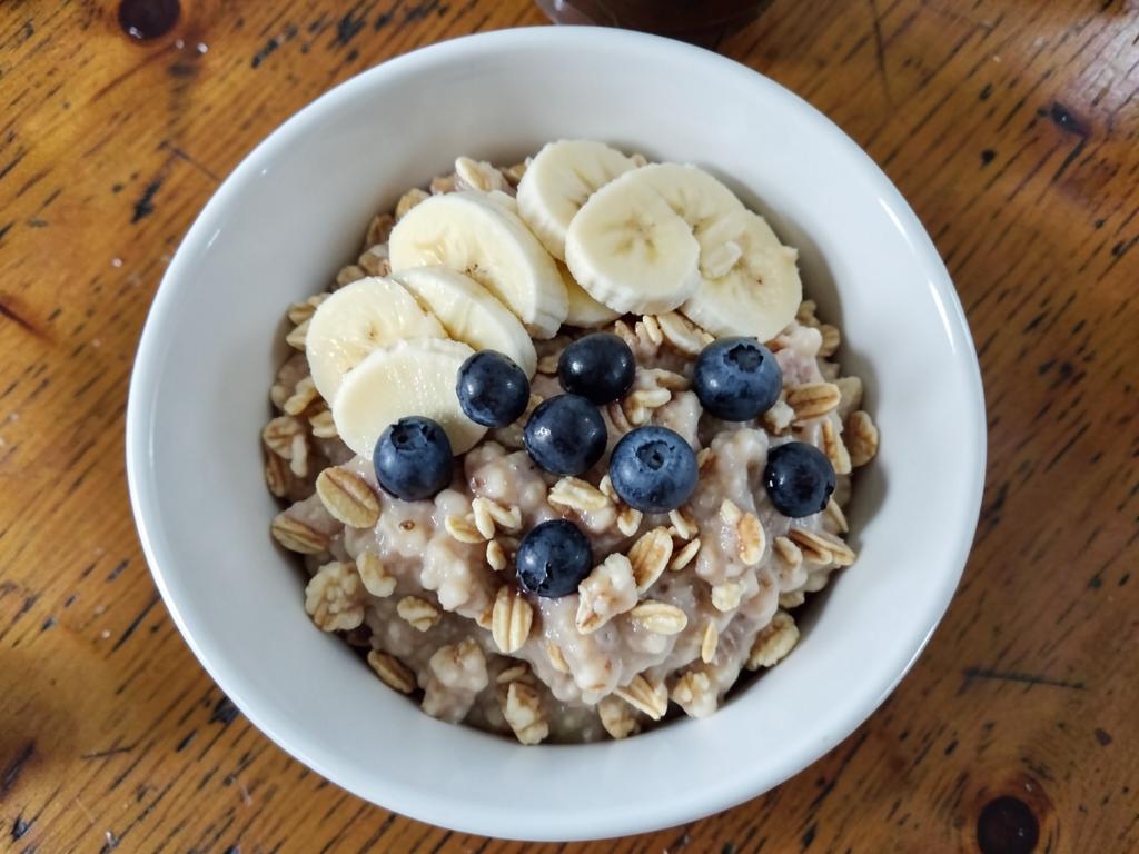 Bowl of oats topped with banana slices and blueberries Bowl of oats topped with banana slices and blueberries