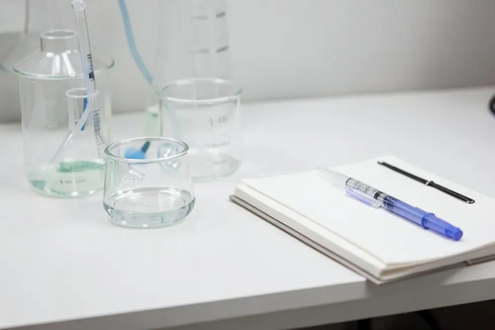 Laboratory glassware and a notebook on a white bench Laboratory glassware and a notebook on a white bench