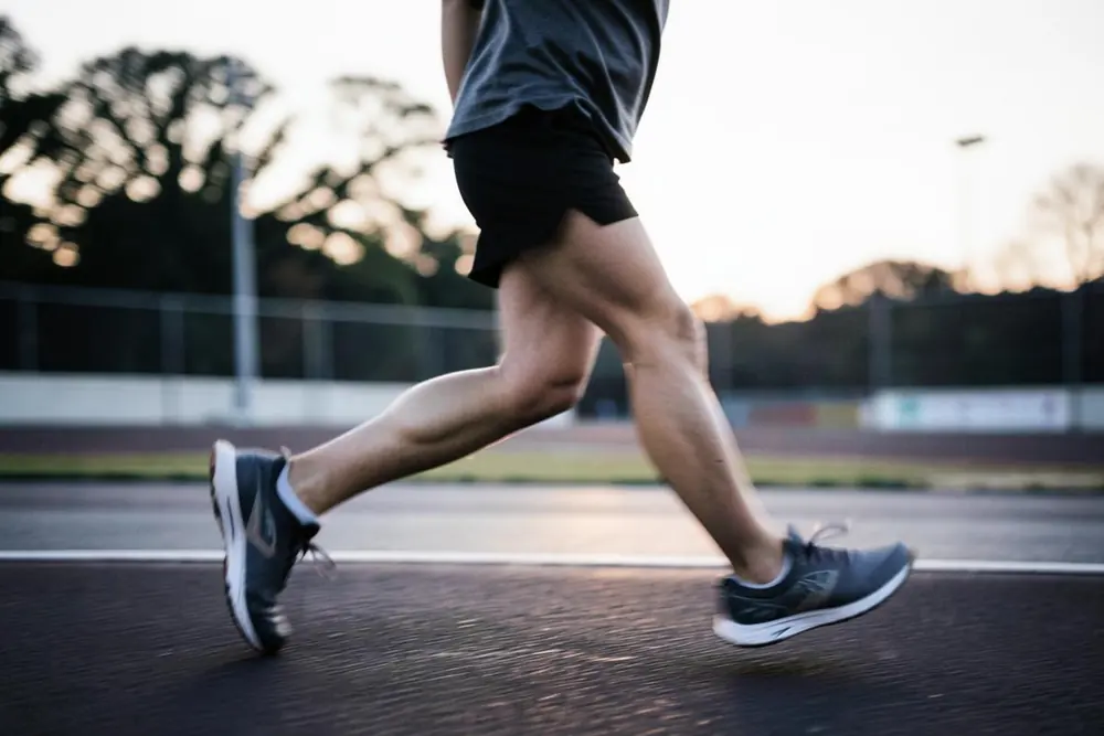A runner's legs mid-stride on an outdoor track at dawn
