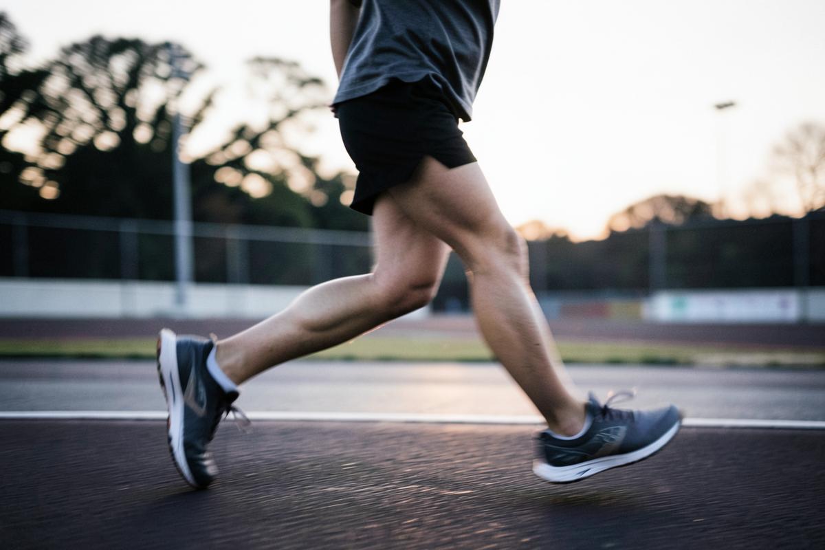 A runner's legs mid-stride on an outdoor track at dawn