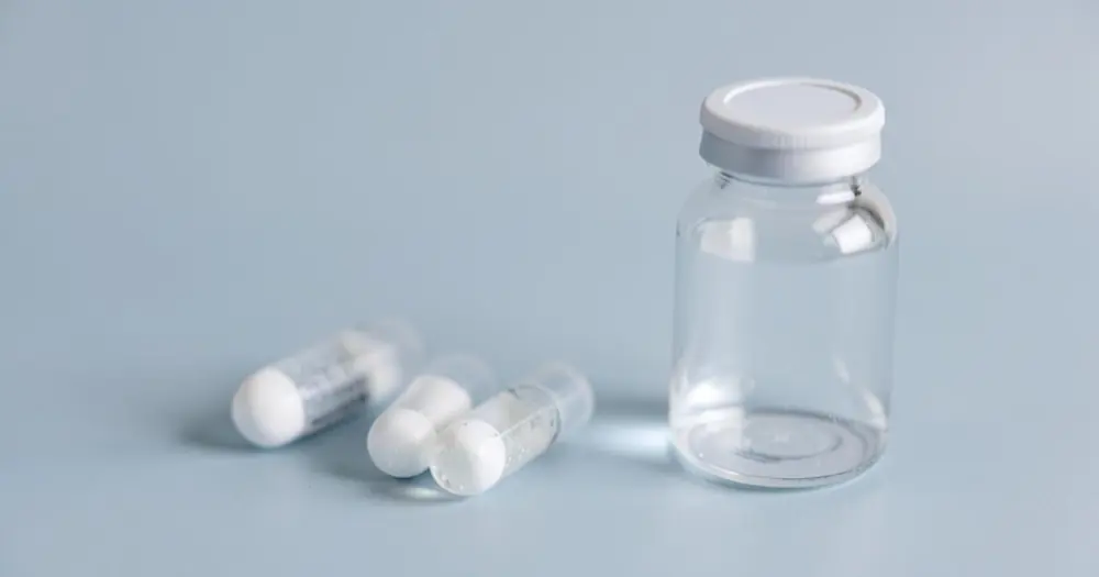 Lyophilized powder vials beside a vial of sterile water on a blue-grey surface Lyophilized powder vials beside a vial of sterile water on a blue-grey surface