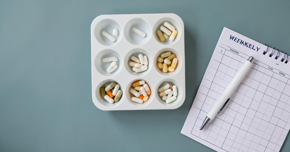 A weekly pill organiser and planner laid out on a desk