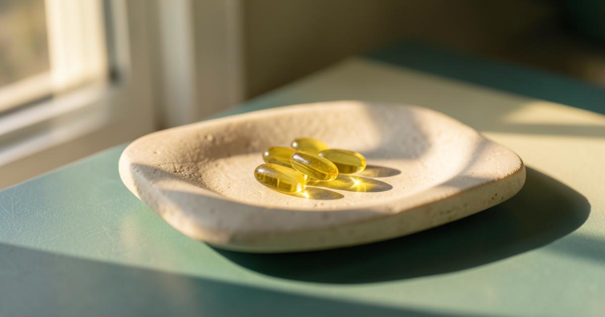 Yellow vitamin D3 softgels on a stone dish in morning sunlight